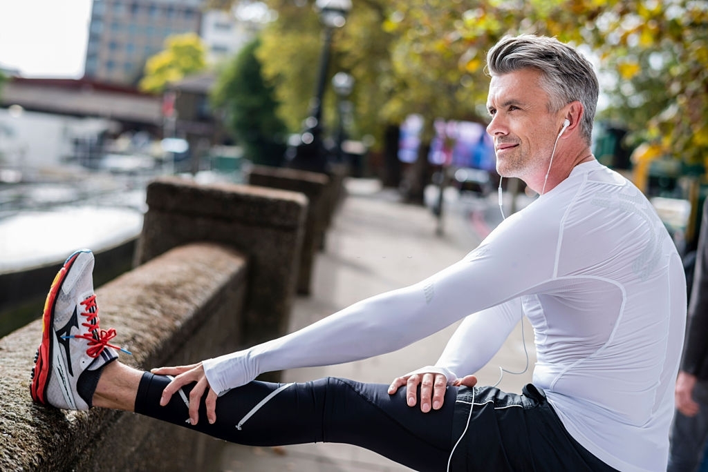 How to Set Realistic Running Goals (and Achieve Them) Man exercising outdoors and stretching his legs