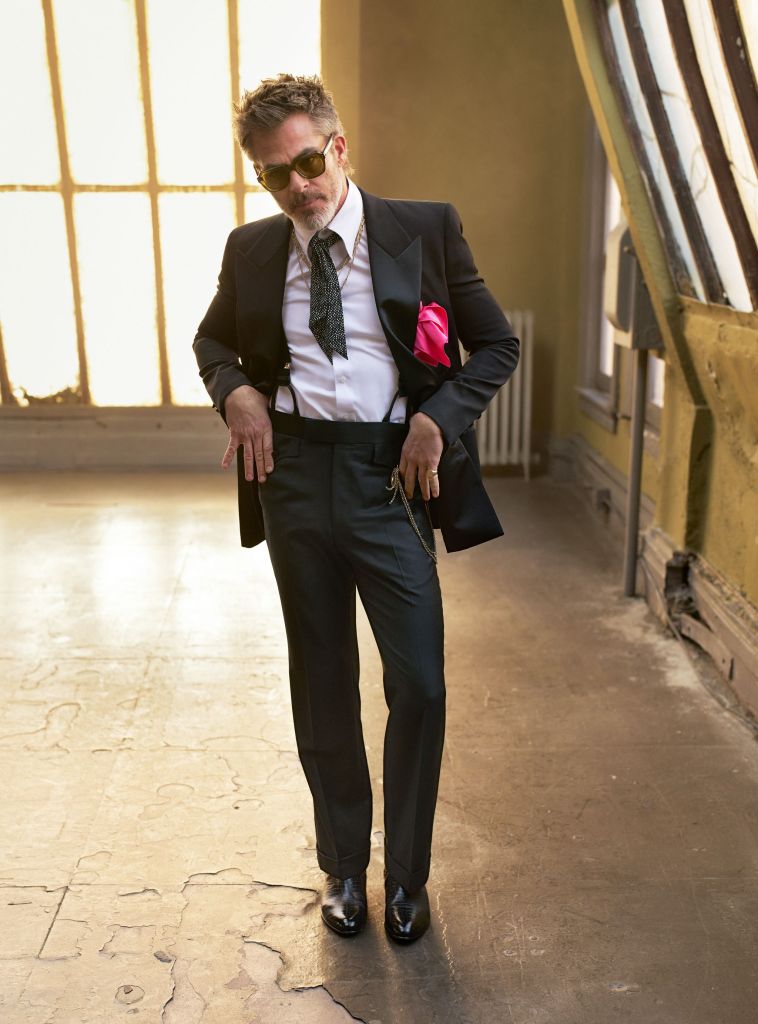 Jacket, Saint Laurent by Anthony Vaccarello; shirt and trousers by Edward Sexton; braces by New & Lingwood; sunglasses by Jacques Marie Mage; boots by Tom Ford; Santos de Cartier necklace and Trinity necklace by Cartier; chain necklace by David Yurman; necklace with pendant and signet ring, Pine’s own; neck tie, pocket square, and watch fob chain, stylist’s own.