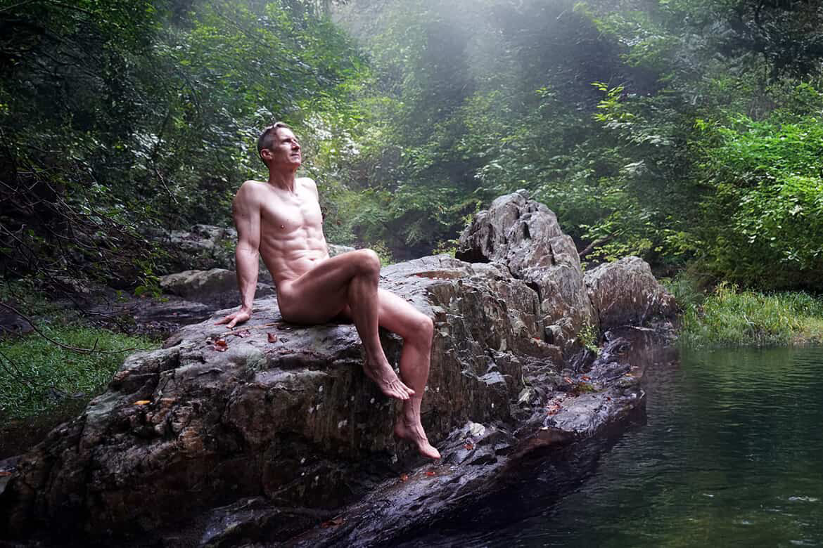 Gymnos poses nude in Prince William Forest Park, captured by @photomandc_3, blending raw masculinity with nature’s serenity.