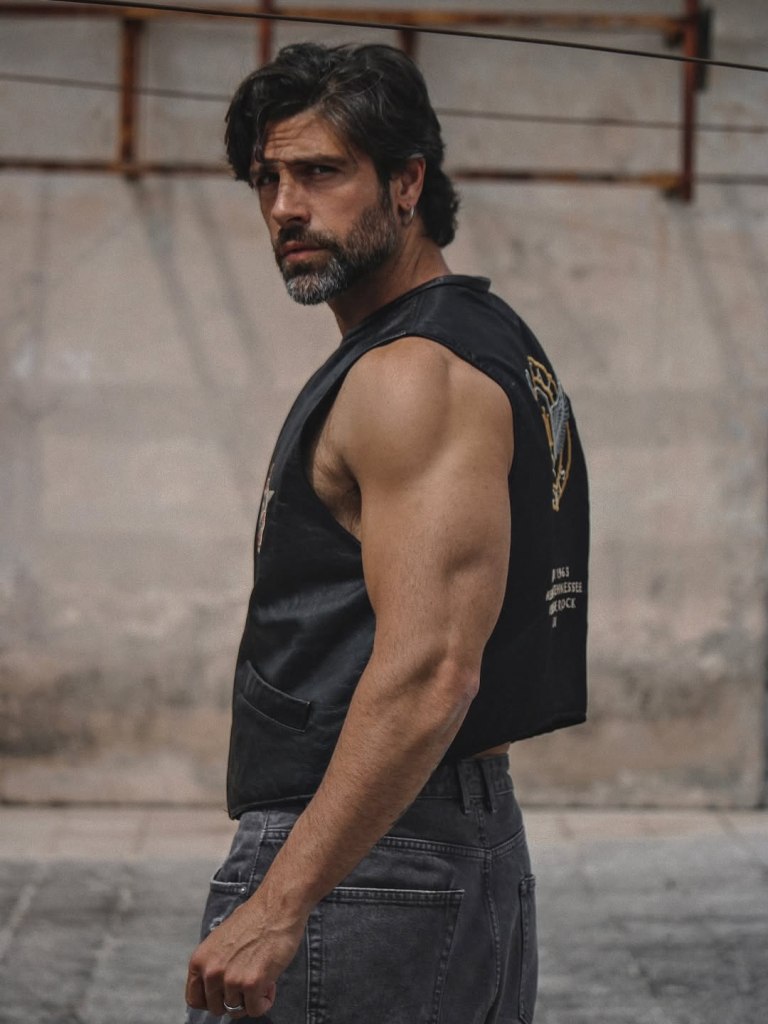 Italian actor Gilles Rocca poses in black-and-white and color portraits photographed by Marco Melfi in Testaccio, Rome, showcasing his hairy chest, muscular physique, and gray-bearded rugged masculinity.