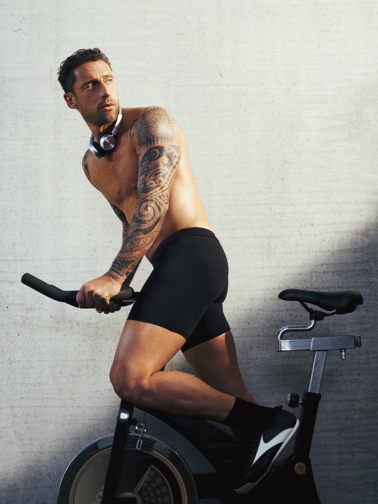 Claudio Marchisio shirtless on an exercise bike wearing black fitted underwear for IUMAN FW 2026.
