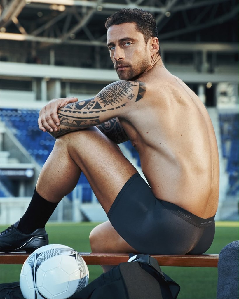 Claudio Marchisio showing his tattooed arms and athletic physique in black boxer briefs beside a football.
